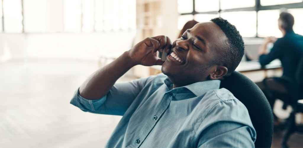 Man sitting back and smiling whilst on phone